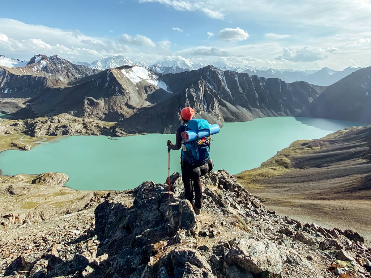 Chica en lo alto Ala Kul, con el lago debajo y siendo una de las fotos más sorprendentes de la ruta de 15 días en Kirguistán 