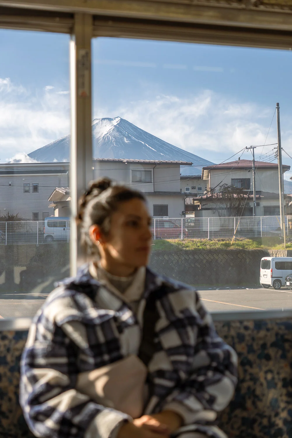 Chica sentada en el tren con el Monte Fuji detrás.