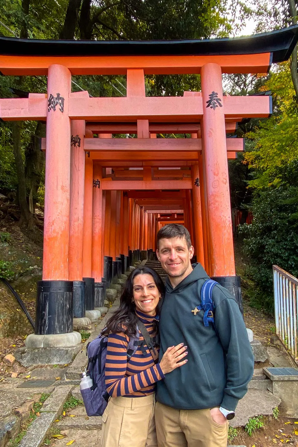 Silvia y David posando frente al acceso de un pasillo con torii de color naranja en Fushimi Inari
