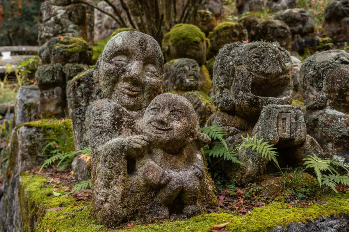 Estatuas en piedra con caritas sonrientes y musgo que las cubre