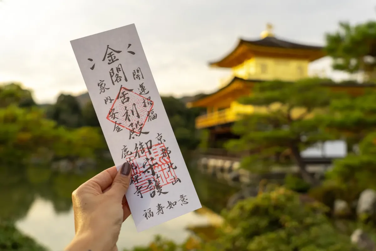 Entrada con caligrafía japonesa para el templo del Pabellón Dorado, y este al fondo