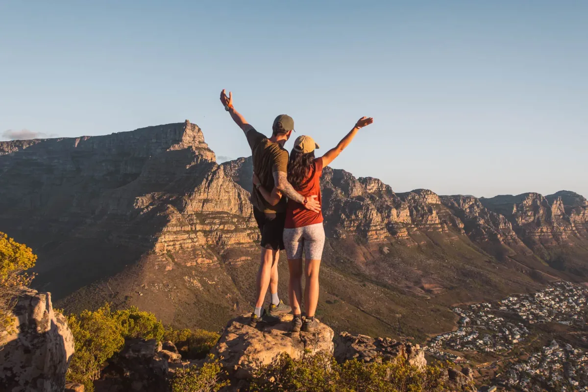 Pareja en lo alto de Lion's Head, el mirador más famoso de Ciudad del Cabo, de espaldas y mirando el paisaje