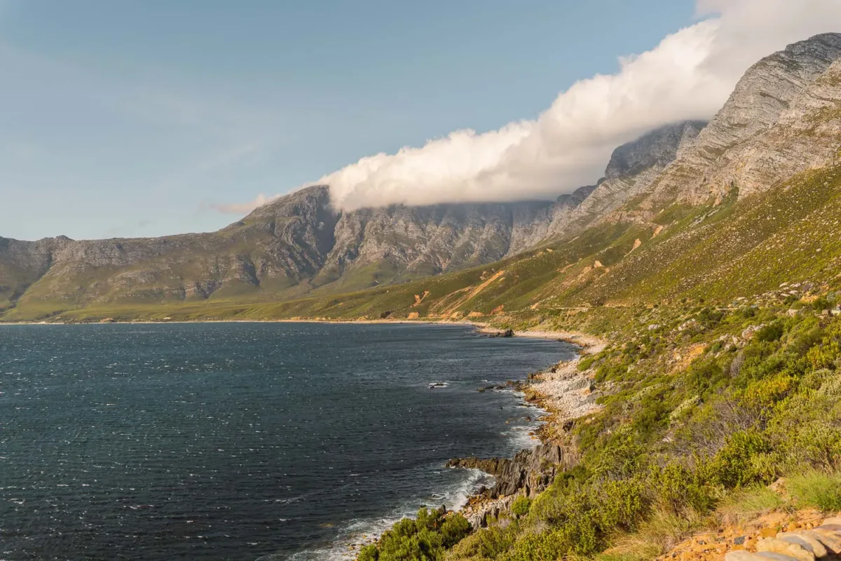 Vistas de un paisaje de Sudáfrica, con el océano y montañas a la derecha.