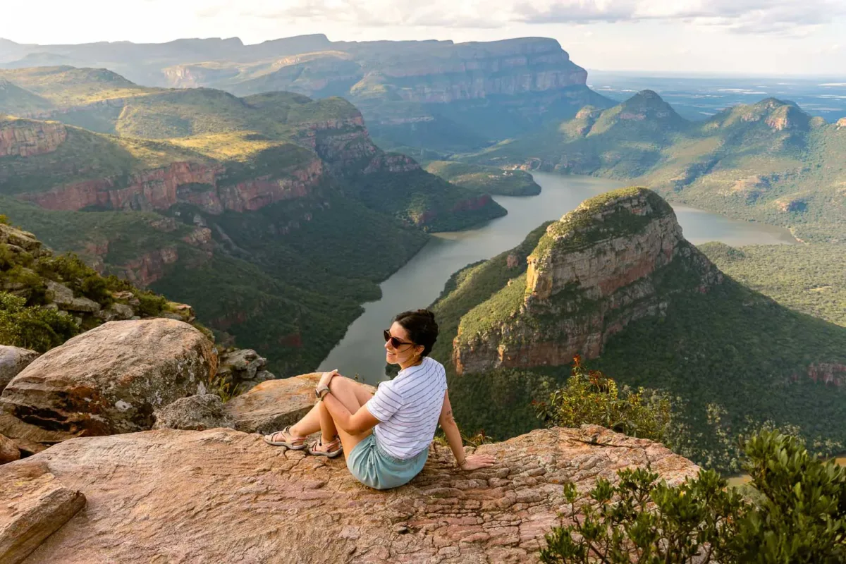 Chica sentada con uno de los paisajes más emblemáticos de la ruta Panorama en Sudáfrica.