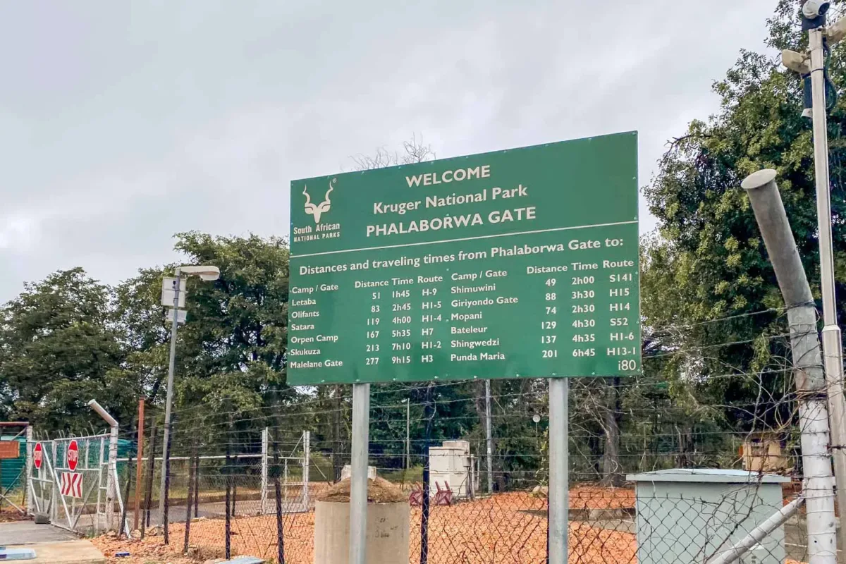 Exterior de la puerta de Phalaworba, en el Kruger con un panel informativo de horas y distancias dentro del parque