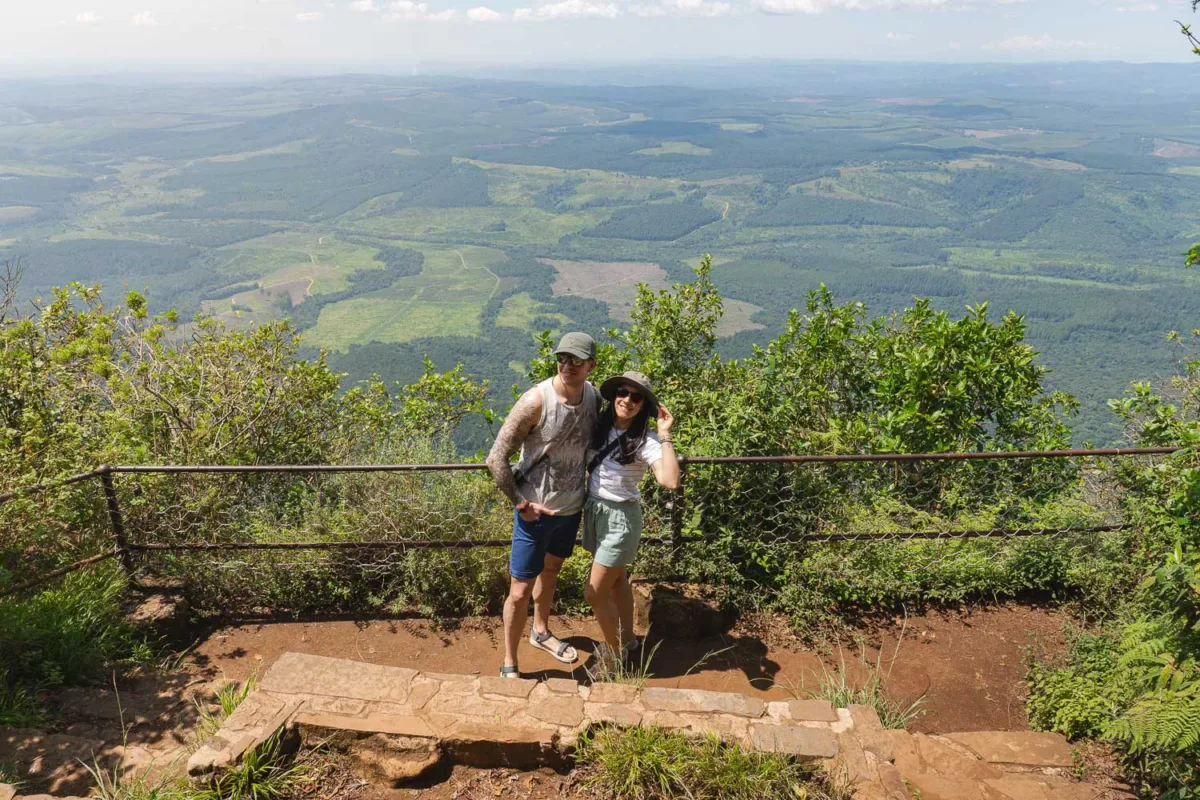 pareja posando en uno de los miradores en God's Window, con un paisaje frondoso y verde al fondo
